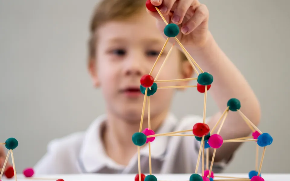 boy-playing-with-colorful-atoms-game-table