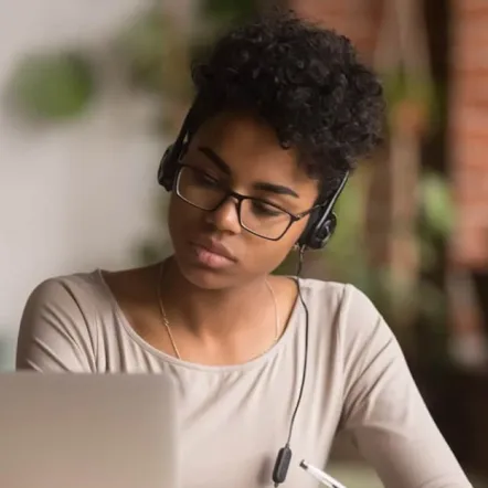 girl holding an exam on her laptop with headphones