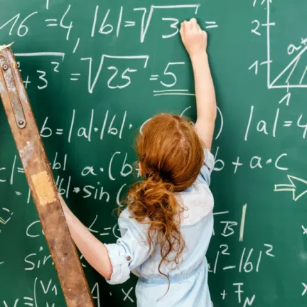 A student solving math problems on a blackboard